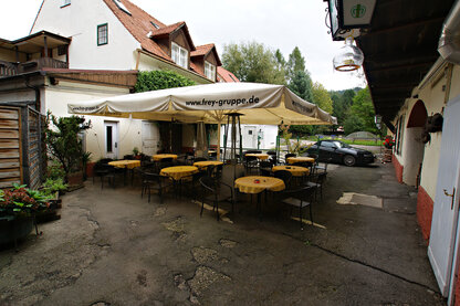 Hof mit Tische & Parkbereich und Garten im Hintergrund Hof mit Tische & Parkbereich und Garten im Hintergrund